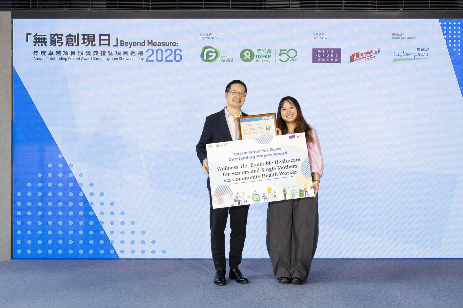Mr Henry Tang Chi-fai (left) presented the "Annual Outstanding Project Award" certificate to the Grant for Good winning project, "Wellness Tie: Equitable Healthcare for Seniors and Single Mothers via Community Health Worker ".