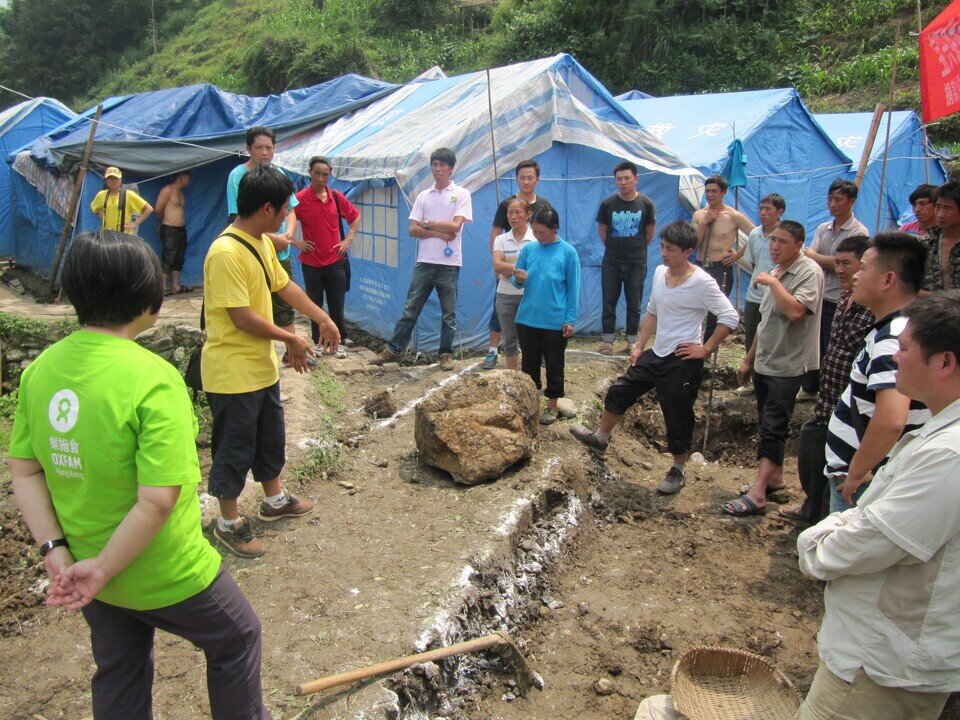 Technicians speak to villagers about how ecosan toilets work as Oxfam unveils a project to improve sanitary conditions at a disaster relief camp. (Oxfam)