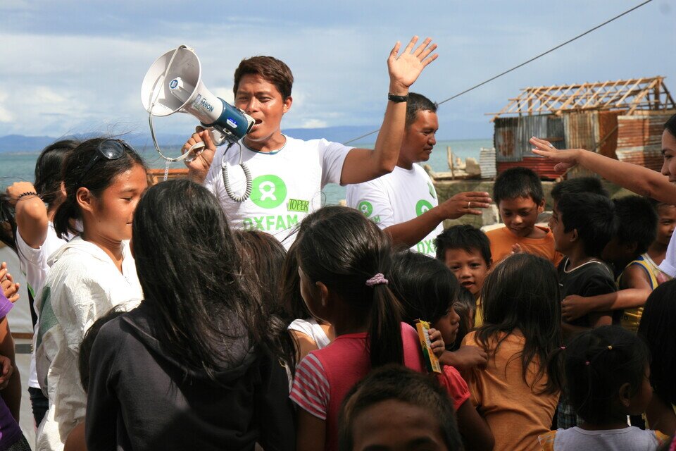 Christoper ‘Toper’ Cabalhiw (left), a local volunteer working with Oxfam as a Public Health Promoter, and Oxfam Public Health Assistant Allan A Nayga (right). Organising children at an Oxfam public health promotion activity aimed at encouraging children to understand why and how to wash their hands and use the latrines. (Jire Carreon/Oxfam)