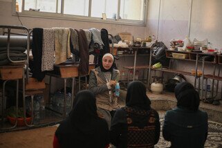 Woman holding bottle speaking to a group of women.