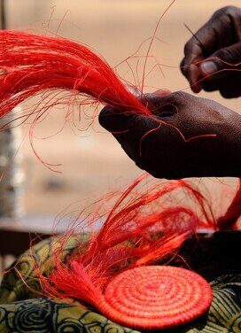 A woman weaving products out of sisal together.