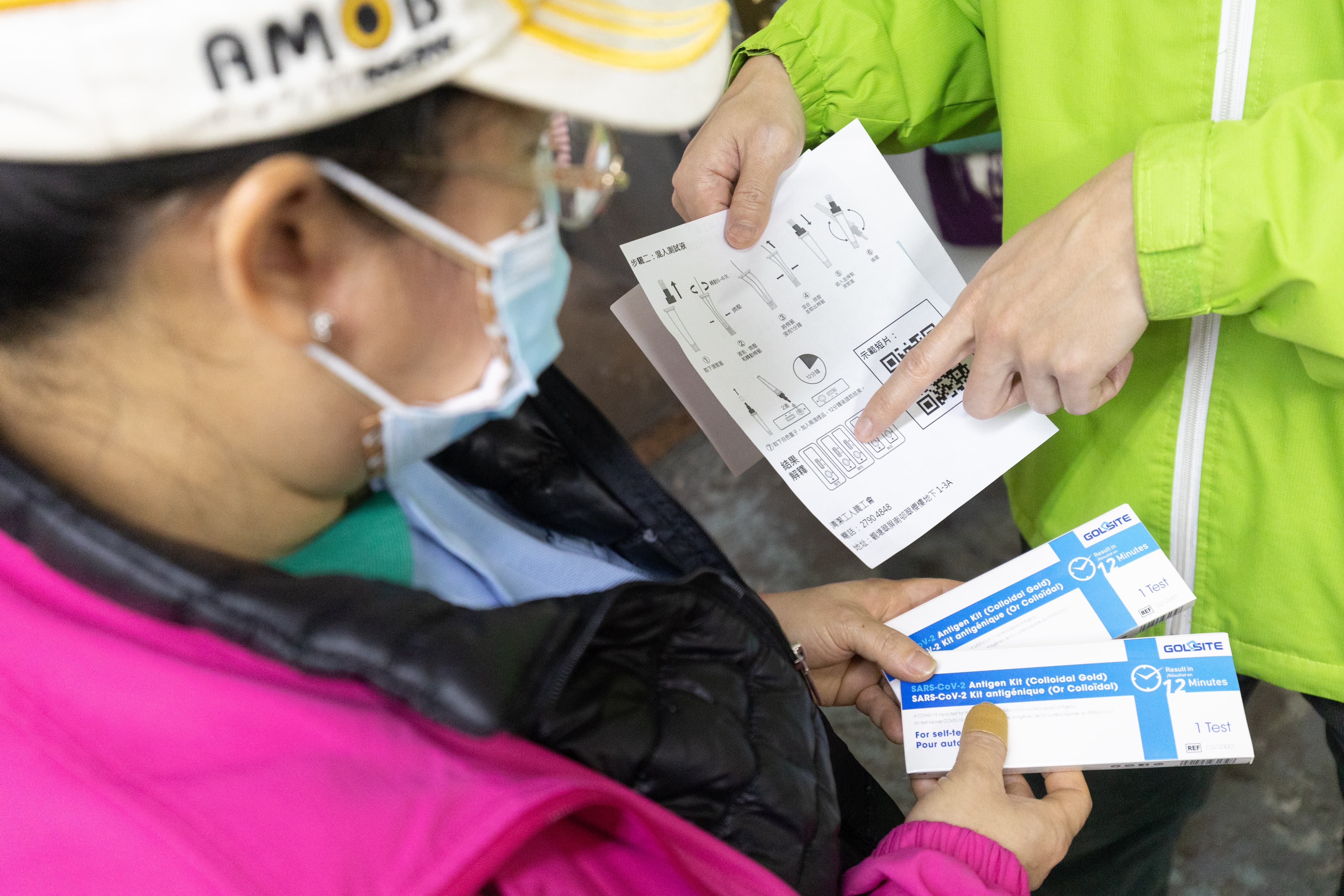 Outsourced cleaner holding COVID test kit.