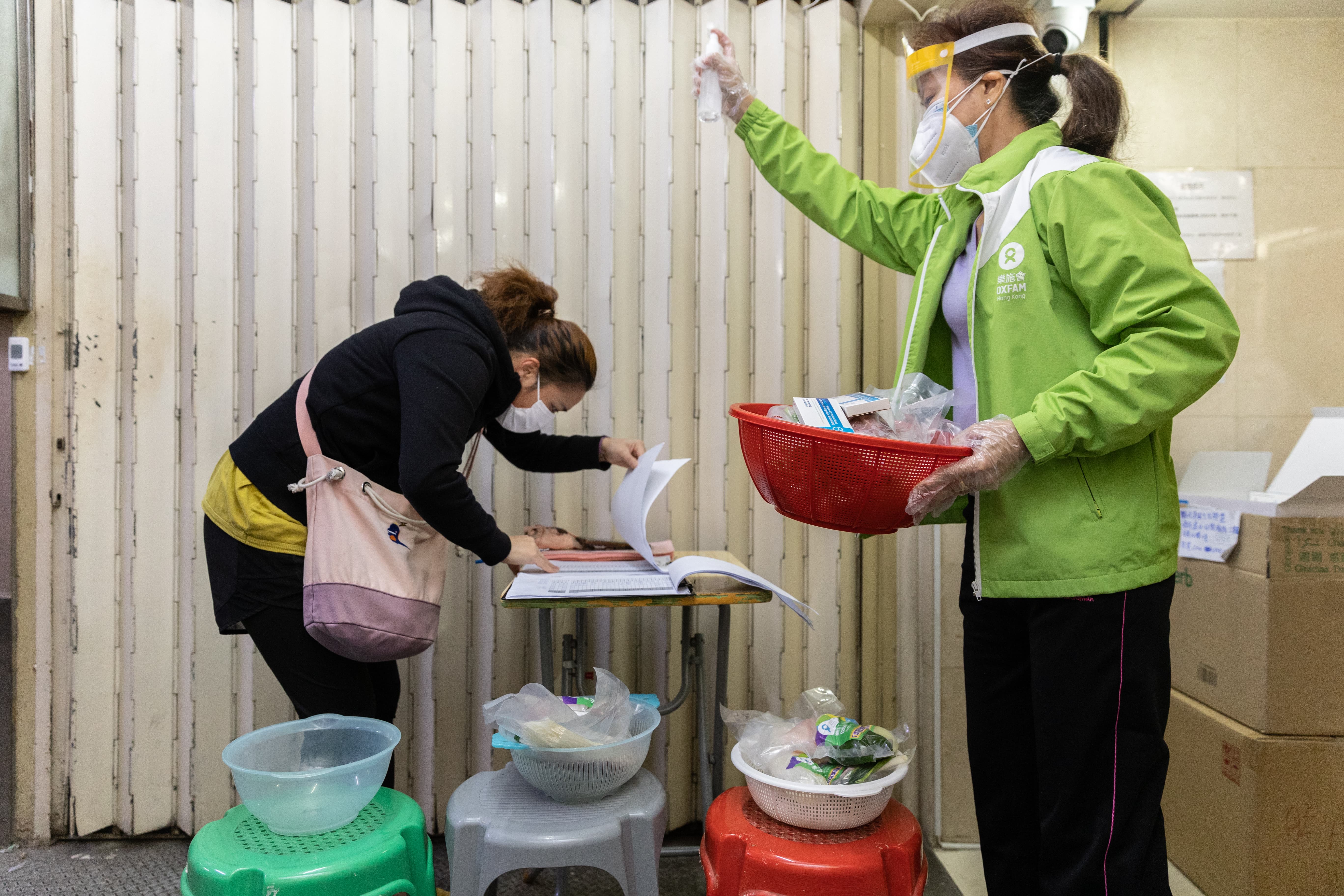 Food project participant confirming that she received the meal kit and COVID test kit, and staff member disinfecting the area